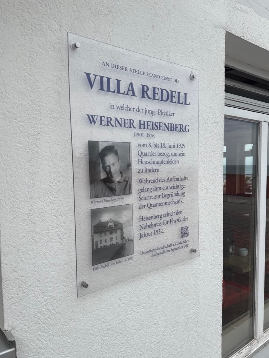 Gedenkschild am Hotel auf den Hummerklippen, Helgoland. Glas-Schild mit Foto des jungen Werner Heisenberg (1925) und einer historischen Aufnahme der Villa Redell von ca. 1925. Aufgestellt von der Heisenberg-Gesellschaft e.V. München im September 2025.